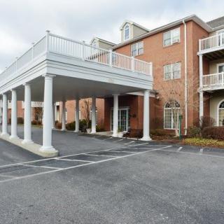 A brick hotel building with a covered driveway and parking lot.