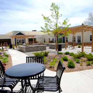 An outdoor patio area with tables and chairs surrounded by landscaped gardens.