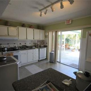 A modern kitchen with white cabinets and a sliding glass door leading to an outdoor area.