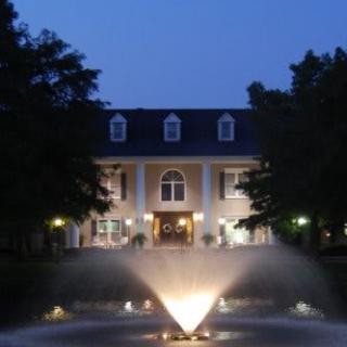 Elegant building with a lit fountain in the foreground during nighttime.