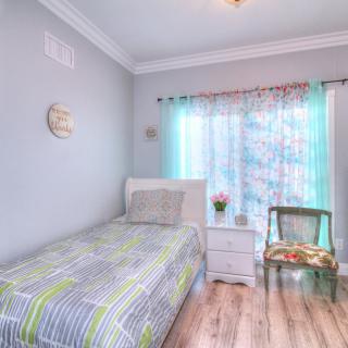 A bright and airy bedroom with a single bed, nightstand, and decorative chair.