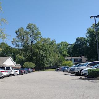 A spacious parking lot surrounded by greenery under a clear blue sky.