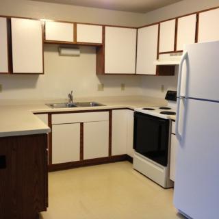 A kitchen with white cabinets, a stove, and a refrigerator.
