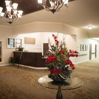A well-decorated lobby featuring a reception desk and floral arrangement under elegant chandeliers.