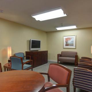 A cozy waiting room with chairs, tables, and a TV.