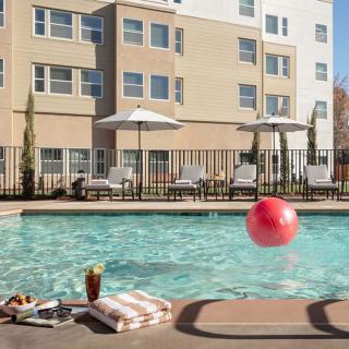 A relaxing hotel swimming pool area with sun chairs and a vibrant red beach ball.