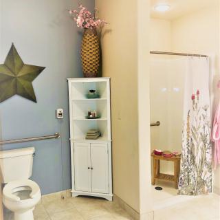 A bathroom featuring a star wall decor, white storage cabinet with pink flowers, and a shower area with a patterned curtain.