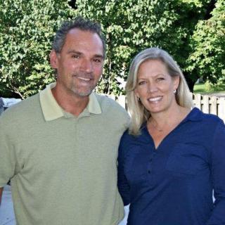 A couple smiling outdoors on a sunny day.