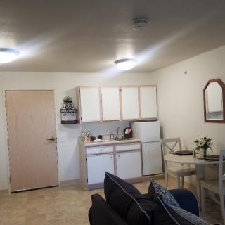 A small apartment kitchen with white cabinets, a table with chairs, and some appliances.