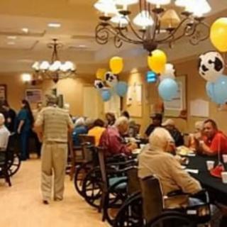 Seniors enjoying a festive gathering with colorful balloons and decor in a nursing home setting.