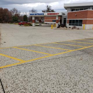 A view of an empty parking lot in front of a commercial building under a cloudy sky.