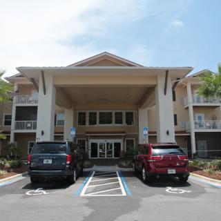 A residential building entrance with parked vehicles in front.