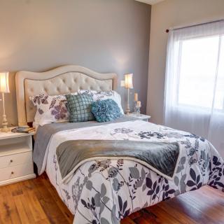A cozy and elegantly decorated bedroom with a tufted headboard, floral bedding, and soft lighting.