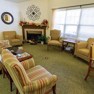 A cozy living room with comfortable chairs and a fireplace, decorated with autumn accents.