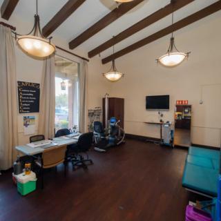 A modern office space with a desk, computer, and seating area under high ceilings.