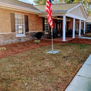 A brick house with an American flag displayed on the front lawn.