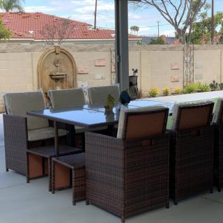 Outdoor patio furniture set with a table and chairs in a backyard setting.