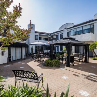 A serene courtyard with outdoor seating and gazebos surrounded by a modern building.