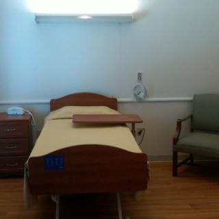 A hospital room with a bed, chair, and medical equipment.