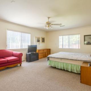 Spacious bedroom with a bed, red sofa, TV, and two large windows.