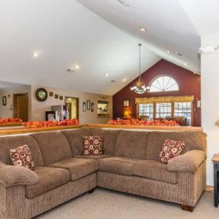 A cozy living room with a large sectional sofa and vaulted ceilings, featuring warm decor and ample natural light.