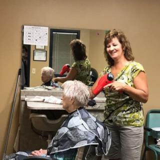 A hairstylist blow-drying a client's hair at a salon.