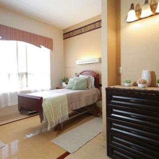 A cozy and well-lit bedroom with a neatly made bed and elegant decor.