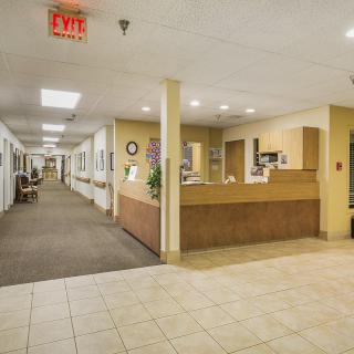 A hospital hallway featuring a reception desk and fluorescent lighting.