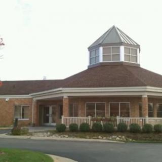 A brick building with a cupola and landscaped entrance.