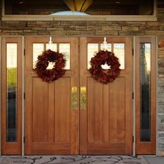 A pair of wooden double doors adorned with autumn wreaths.