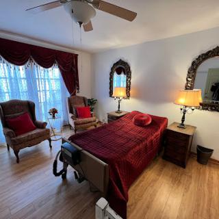 A cozy bedroom featuring a bed with red bedding, elegant mirrors, and a comfortable seating area.
