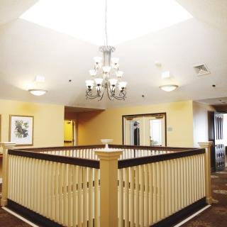 A brightly lit interior hallway featuring a central chandelier and wooden railings.