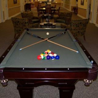 A billiard table set up with cue sticks and balls in a game room.