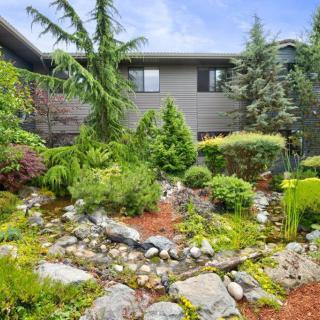 A beautifully landscaped garden with lush greenery and rocks in front of a house.