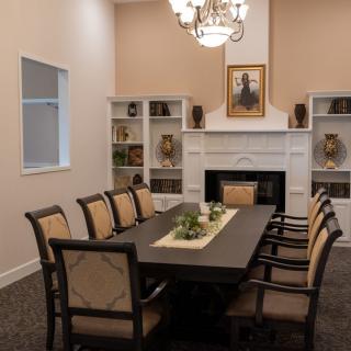A well-decorated dining room featuring a large table, chairs, a chandelier, and a fireplace with surrounding bookshelves.