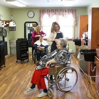Elderly individuals receiving care and grooming in a community care facility.