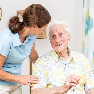 A caregiver interacting with an elderly man at home.