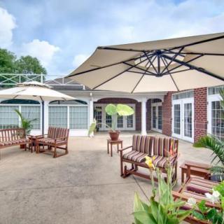 A spacious patio area with wooden seating and large umbrellas, surrounded by a brick building and decorated with potted plants.