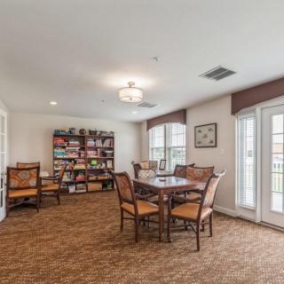 A cozy library room with a table, chairs, and bookshelves.