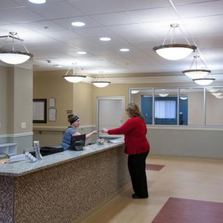 A reception area with two people interacting at the front desk.