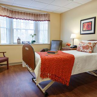 A cozy hospital room with a single bed, bright window, and comfortable furnishings.