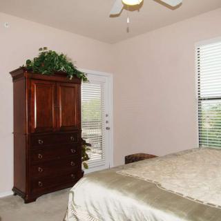 A tidy bedroom with a wooden wardrobe, large bed, and window with blinds.