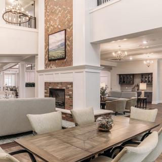 A luxurious modern open-space living room featuring a dining area, fireplace, and elegant chandeliers.