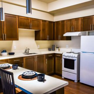 A modern kitchen with wood cabinets and a dining area.