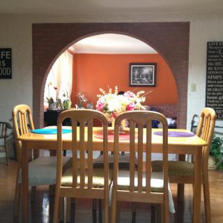A cozy dining room with a wooden table and chairs, featuring a colorful flower arrangement under an archway.