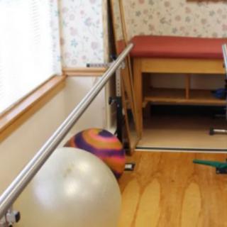 A physical therapy room equipped with parallel bars and an exercise ball.