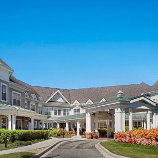 Front view of a large building with a landscaped entrance under a clear blue sky.