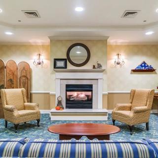 A cozy living room with a central fireplace, surrounded by armchairs and a coffee table.