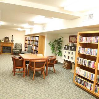 A cozy library interior with bookshelves, a table, and chairs for reading.