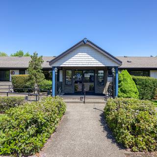 A building entrance surrounded by lush greenery on a clear day.